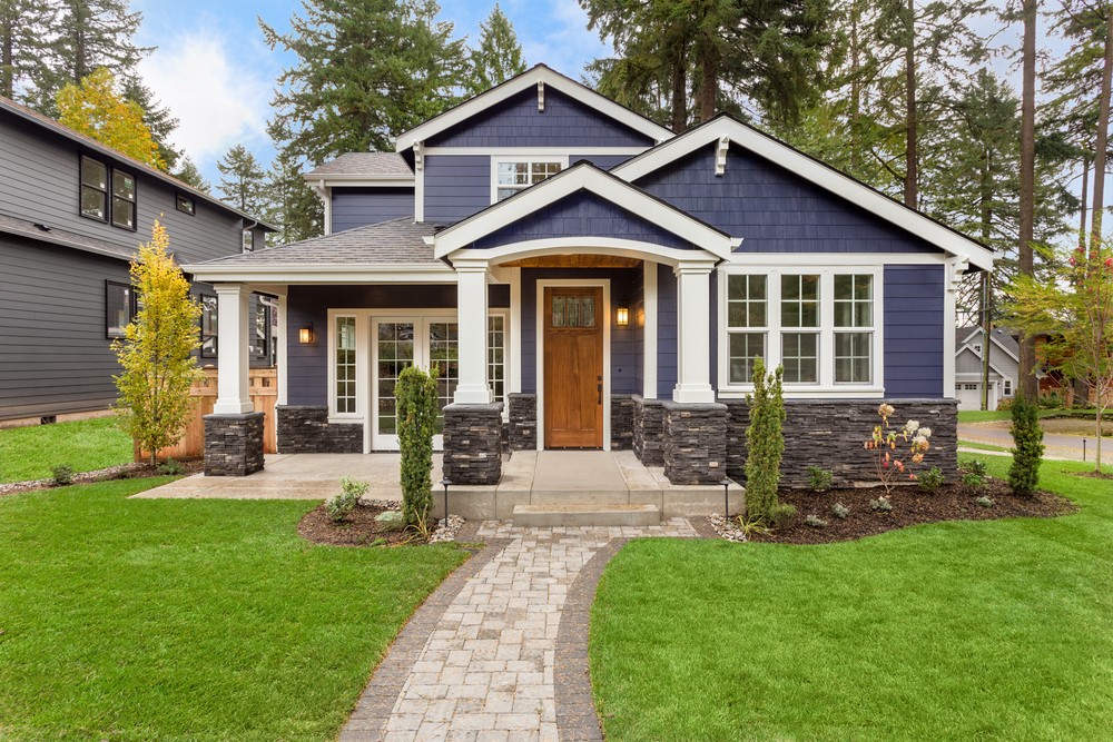 The front exterior of a blue and white two-story house with a spacious front yard.