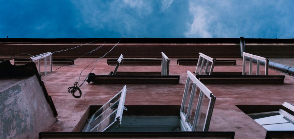 Open windows in a large home or apartment complex, with hanging wires and possible window damage that could lead to a home inspector E&O insurance claim.