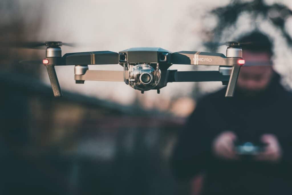 Drone being operated by remote control by man blurred in background
