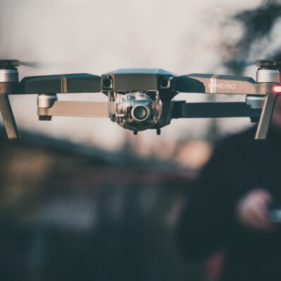 Drone being operated by remote control by man blurred in background