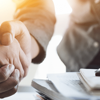 Your Pre-Inspection Agreement: Arbitration, represented with image of the sleeve of a man's grey business suit, reaching out to shake hand of person on the other side of a table