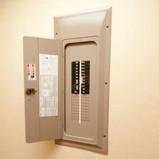 Open electrical panel on an off-white wall