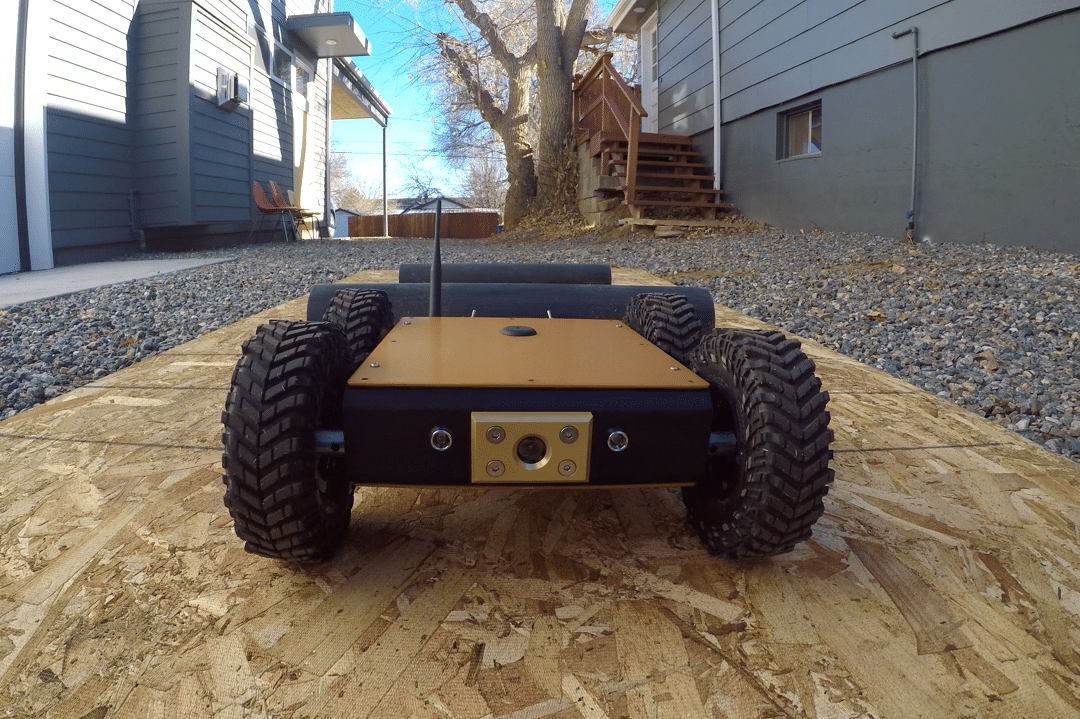 Close up of crawl bot moving toward camera, driving across plank of wood