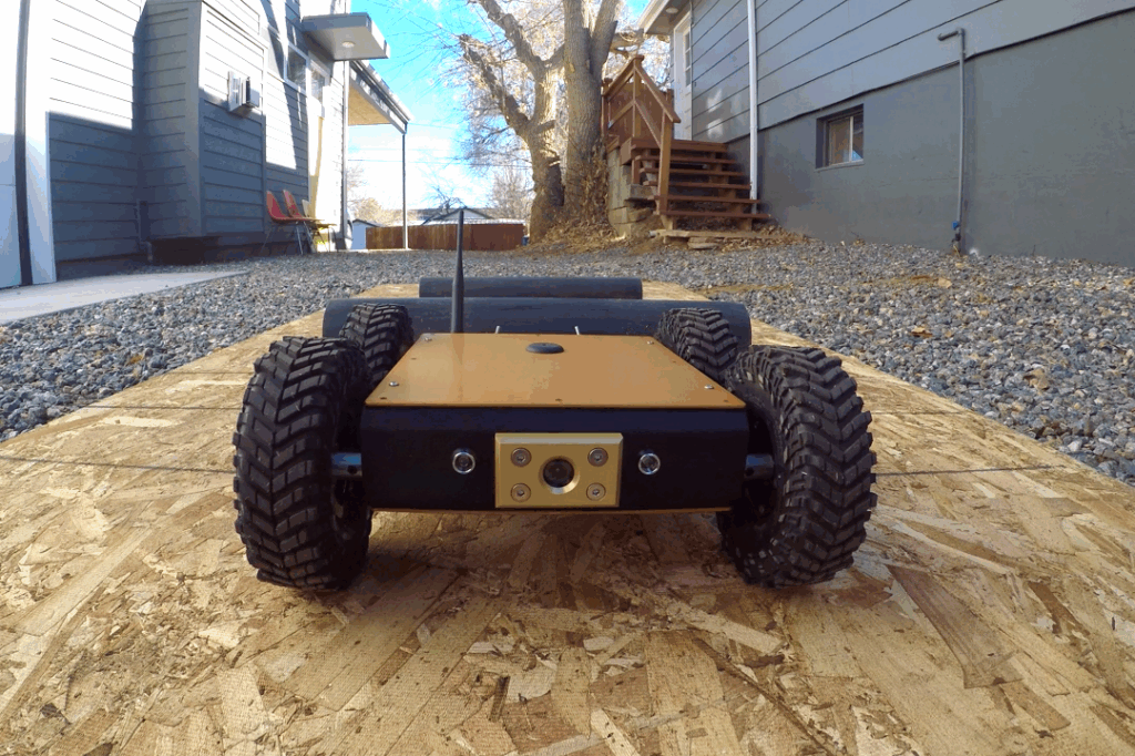 Close up of a crawlspace inspection robot or crawlspace crawler moving toward camera, driving across plank of wood.