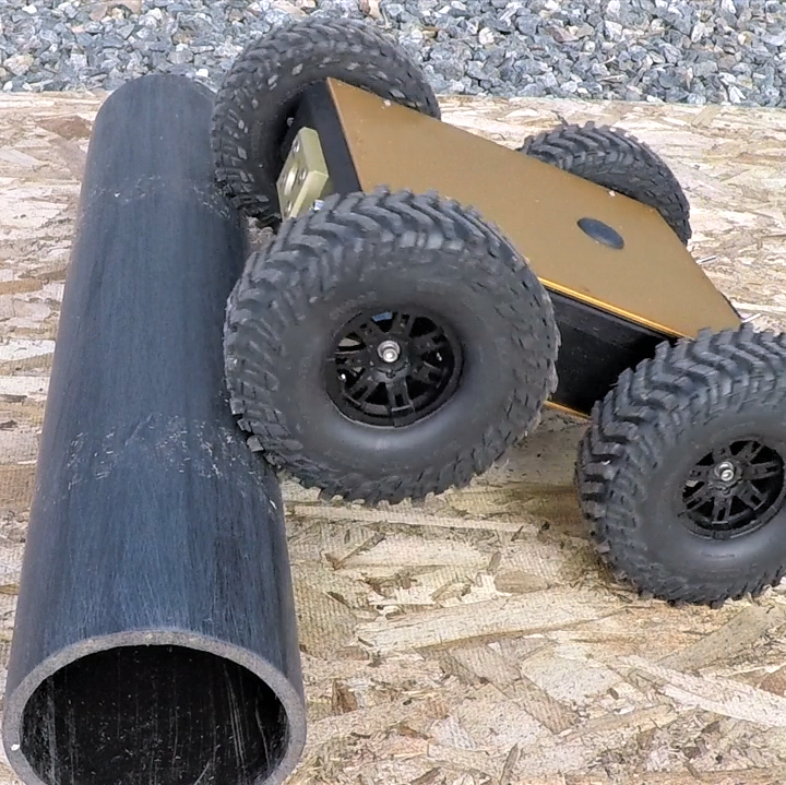 Remote control car with camera for crawlspaces or other inspection spaces, crawling over a pipe.