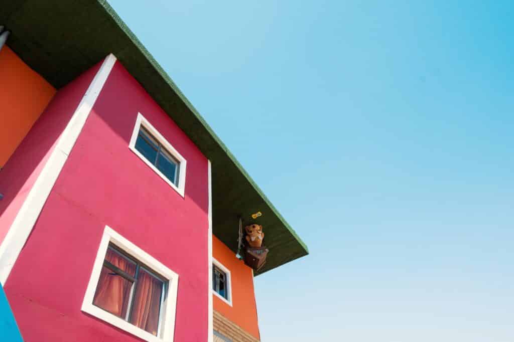 Modern house with bright pink and orange exterior walls that represents a flipped home