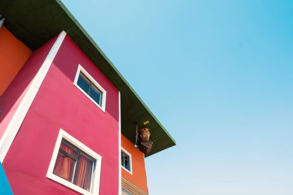 Red and orange house with illusion of being upside down, blue sky in background