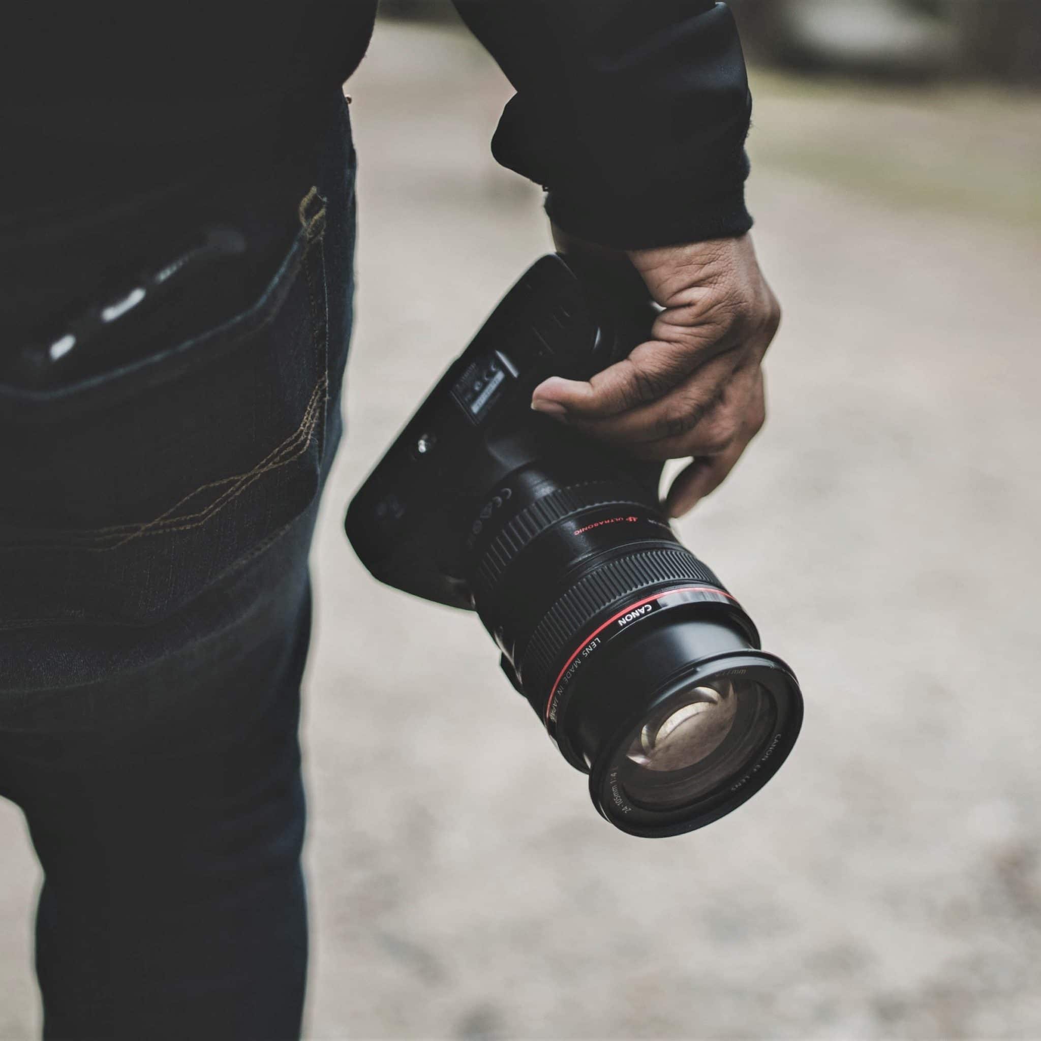 Camera for photographing flipped home inspections, in hand of man with black sweater and dark jeans. Face not visible.