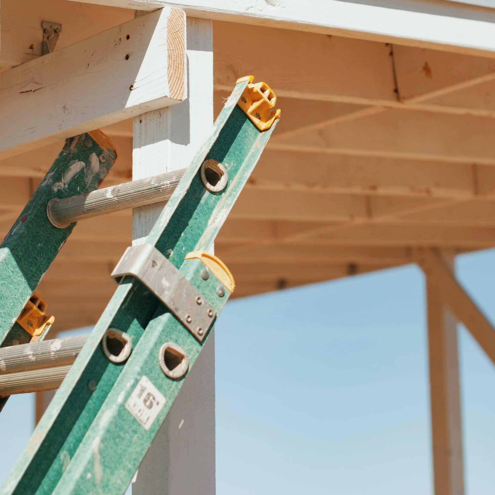 Green ladder leaning against wooden post