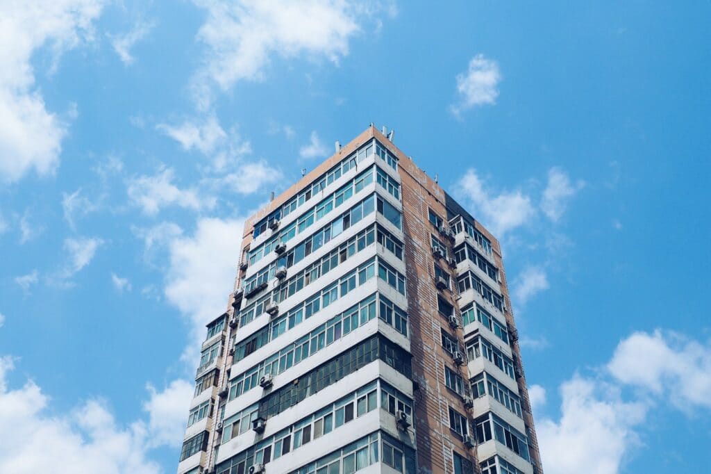 Tall, modern skyscraper for apartments or condos, set against a blue sky with clouds