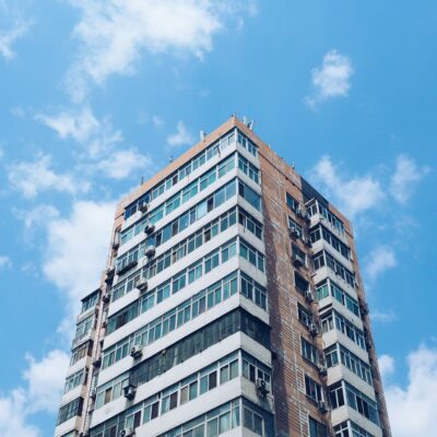 Tall, modern skyscraper for apartments or condos, set against a blue sky with clouds