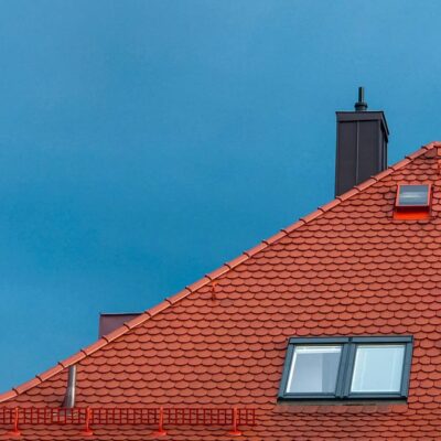 Tall, steep, red roof against a blue sky, communicating a situation that may call for a pole cam