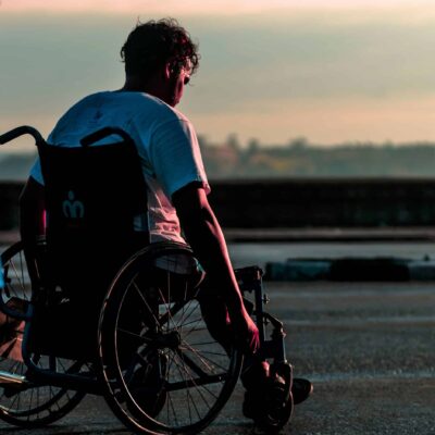 Person with short, curly hair navigating an injury or physical disability in a wheelchair, reflecting the value of workers compensation insurance for work injuries