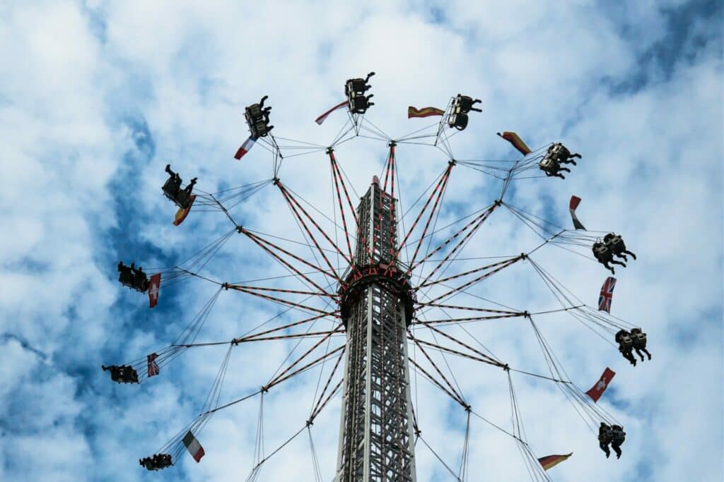 Amusement park or fair ride where seated people are swung in a circle high off the ground. Set against a dark blue sky with clouds.