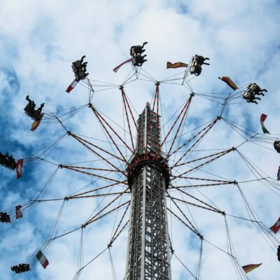 Amusement park or fair ride where seated people are swung in a circle high off the ground. Set against a dark blue sky with clouds.