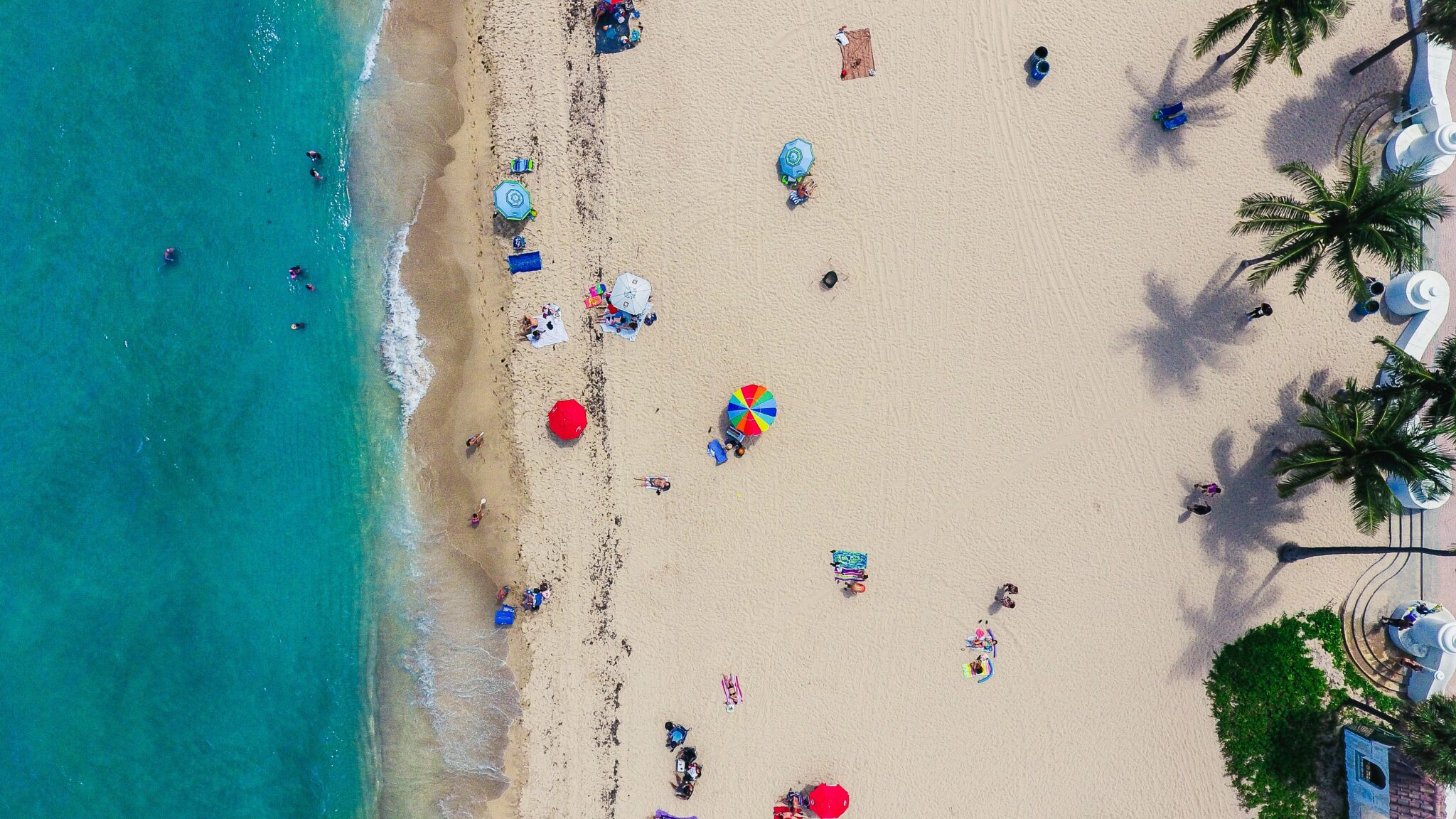 Aerial view of people on a beach along an ocean shoreline on a sunny day