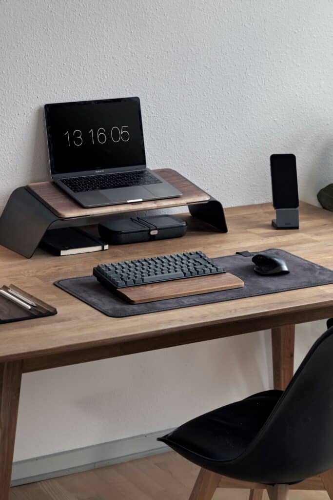 Desk with raised laptop and dark keyboard and mouse