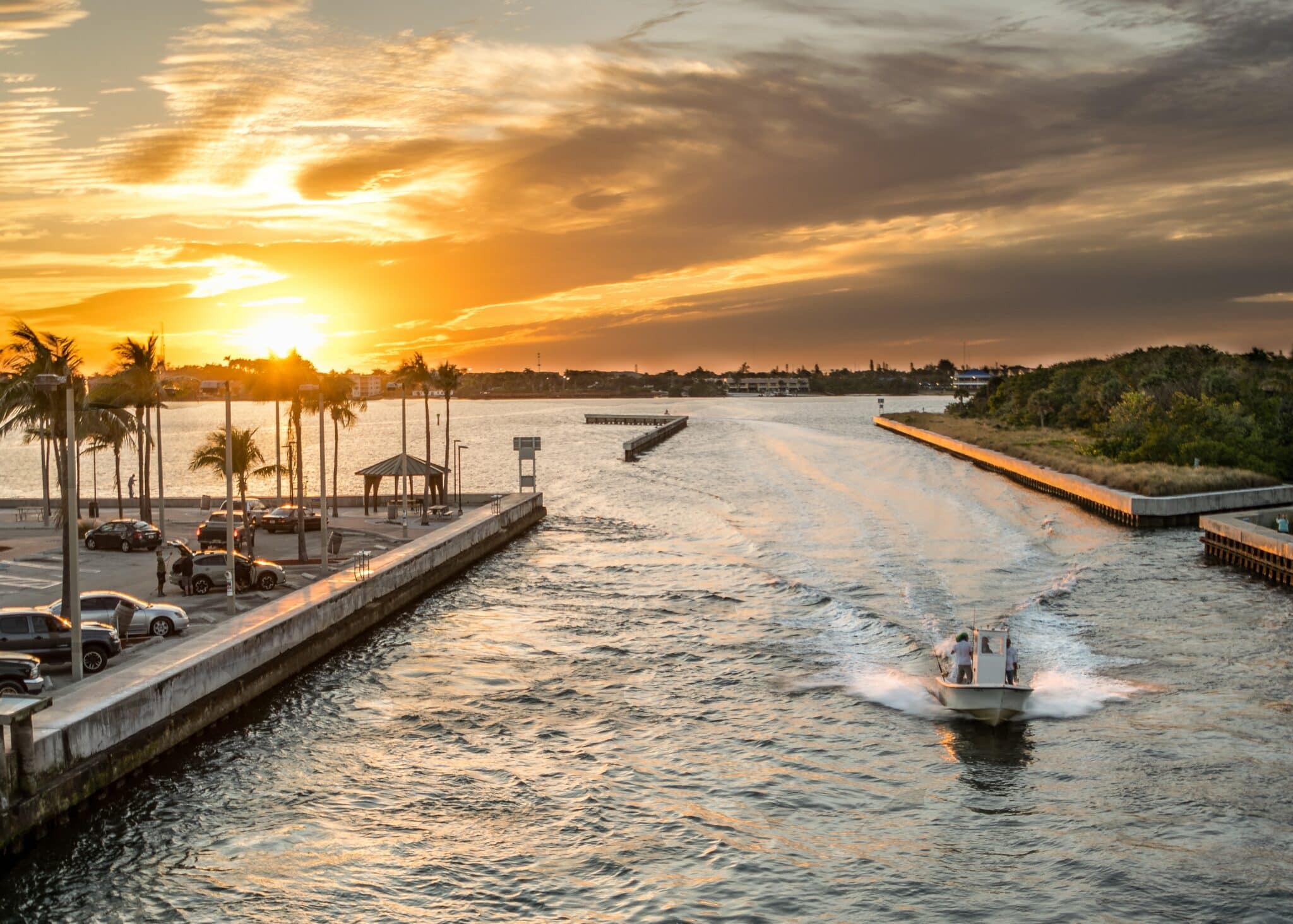 Beach at sunrise or sunset surrounding a parking lot with a small boat passing by the camera