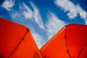 two red umbrellas with blue sky and clouds