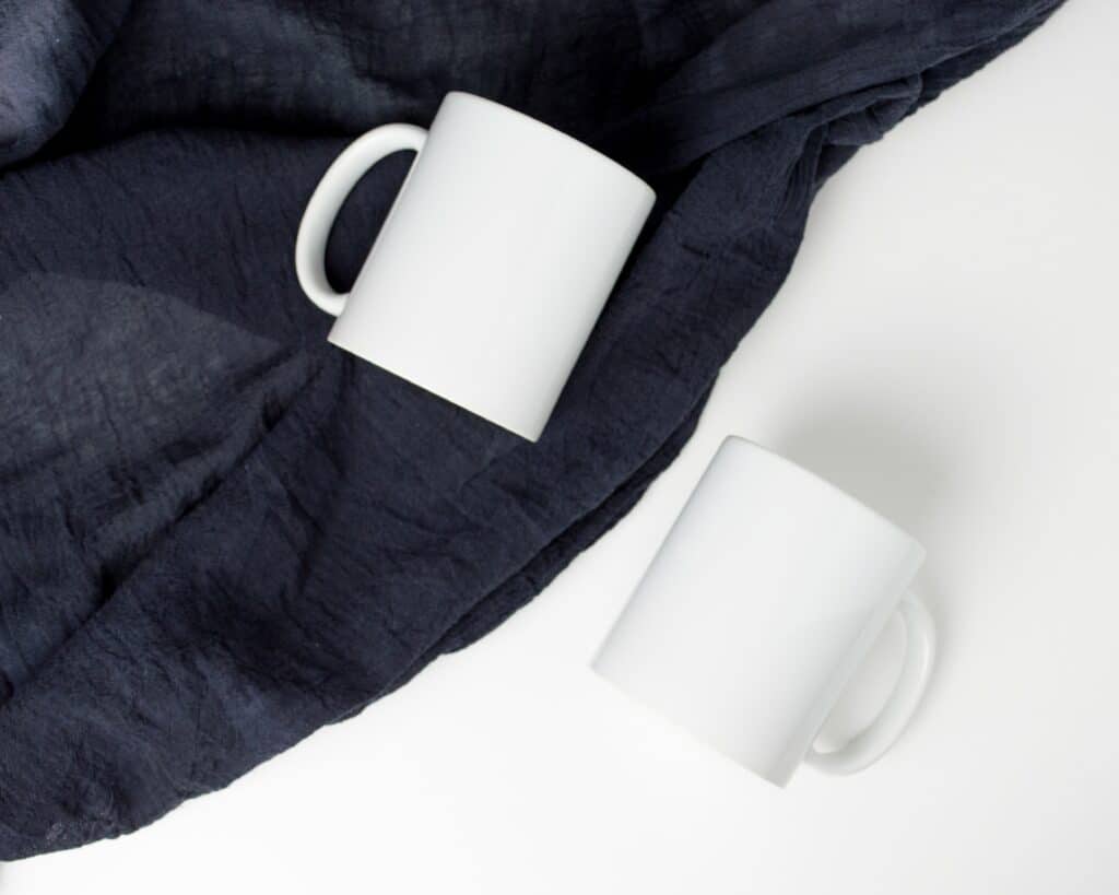 two white mugs one one blanket