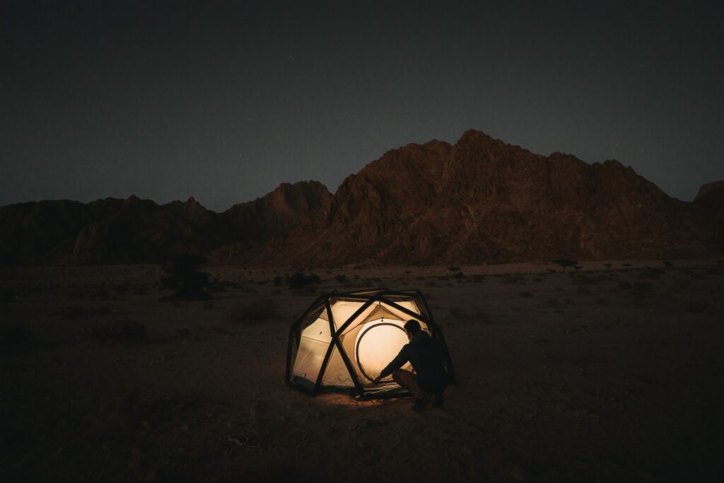 man beside lit up tent at night