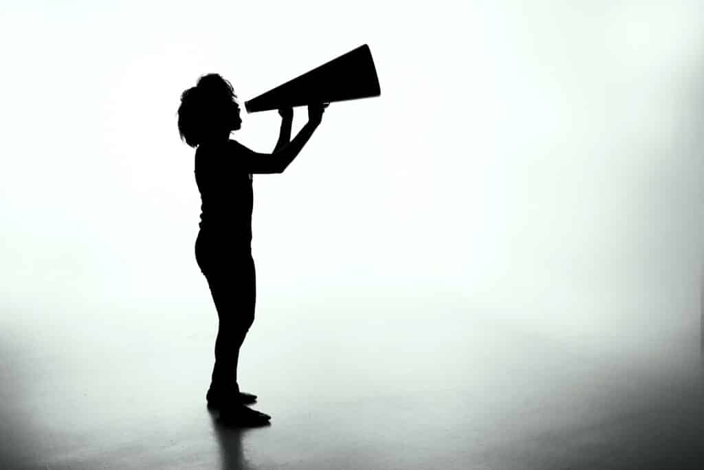 Shadowed figure of a child with thick, curly hair holding a megaphone and speaking into it, as if shouting a liability disclaimer.