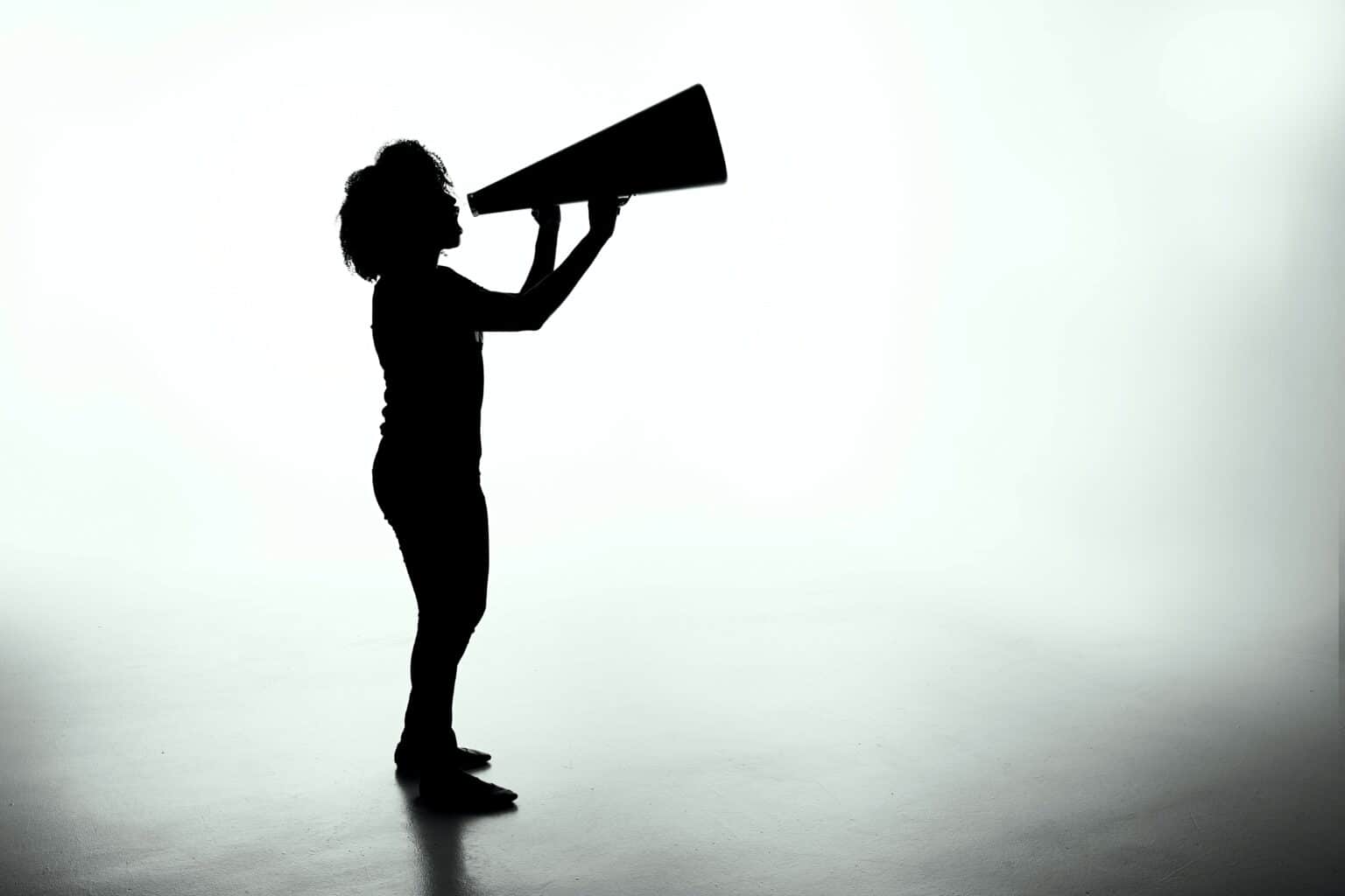 home-inspection-disclaimer-patrick-fore-5YU0uZh43Bk-unsplash Shadowed figure of a child with thick, curly hair holding a megaphone and speaking into it, as if shouting a liability disclaimer.