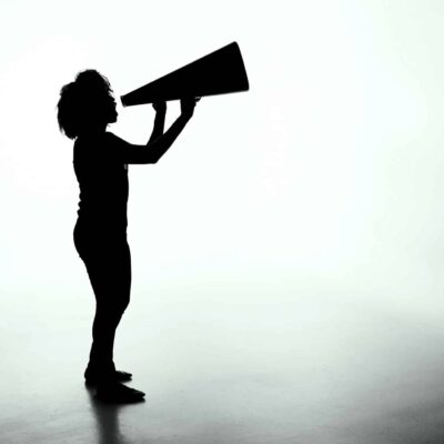Shadowed figure of a child with thick, curly hair holding a megaphone and speaking into it, as if shouting a liability disclaimer.