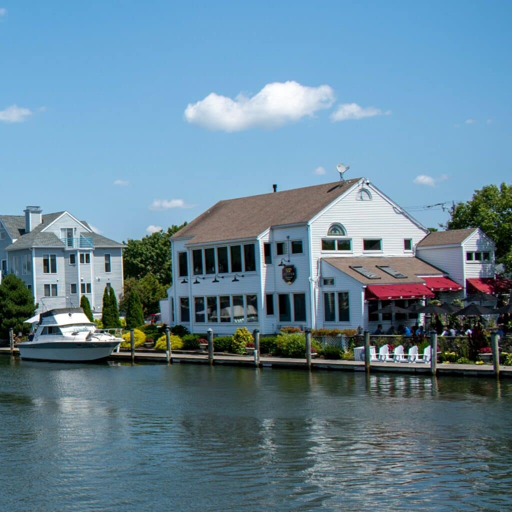 Blue waters of Mystic, Stonington, CT near a dock, with tall, white and blue buildings offering waterfront views for tourists and boaters.