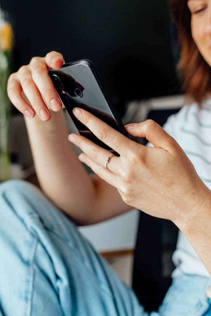 Woman holding and smiling down at a black smartphone