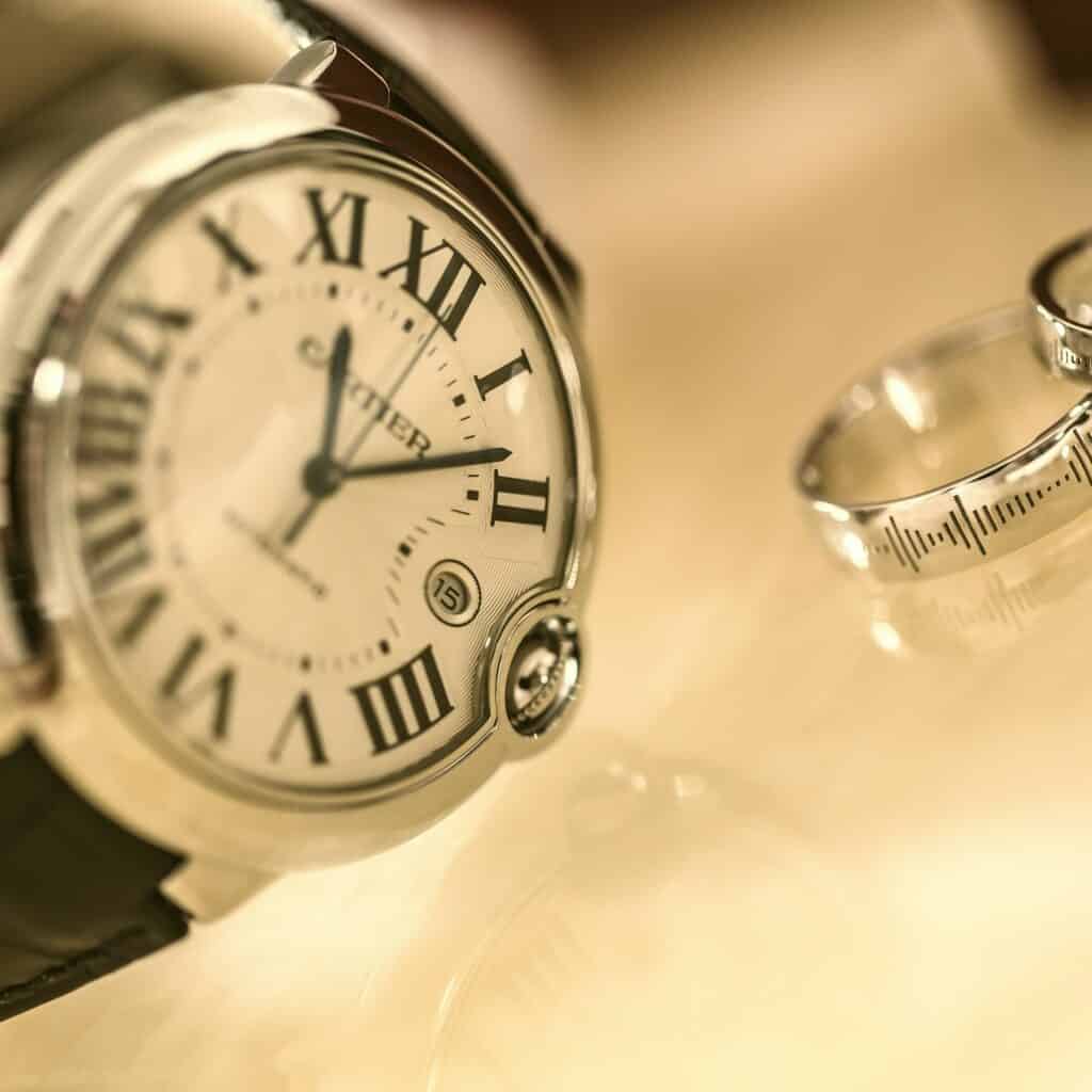 Close-up image of silver watch with black band and two silver wedding bands