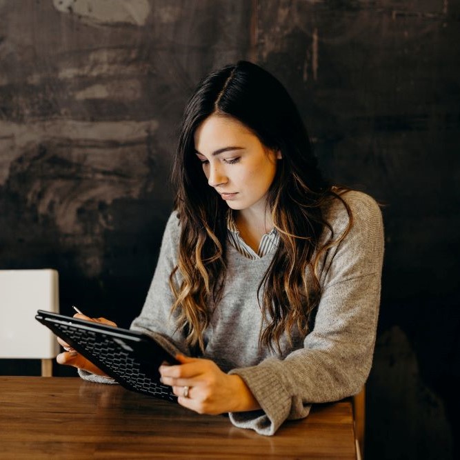 Woman reading a tablet, as a home inspection client would to get clear expectations of underground oil tanks in an inspection agreement they're signing.