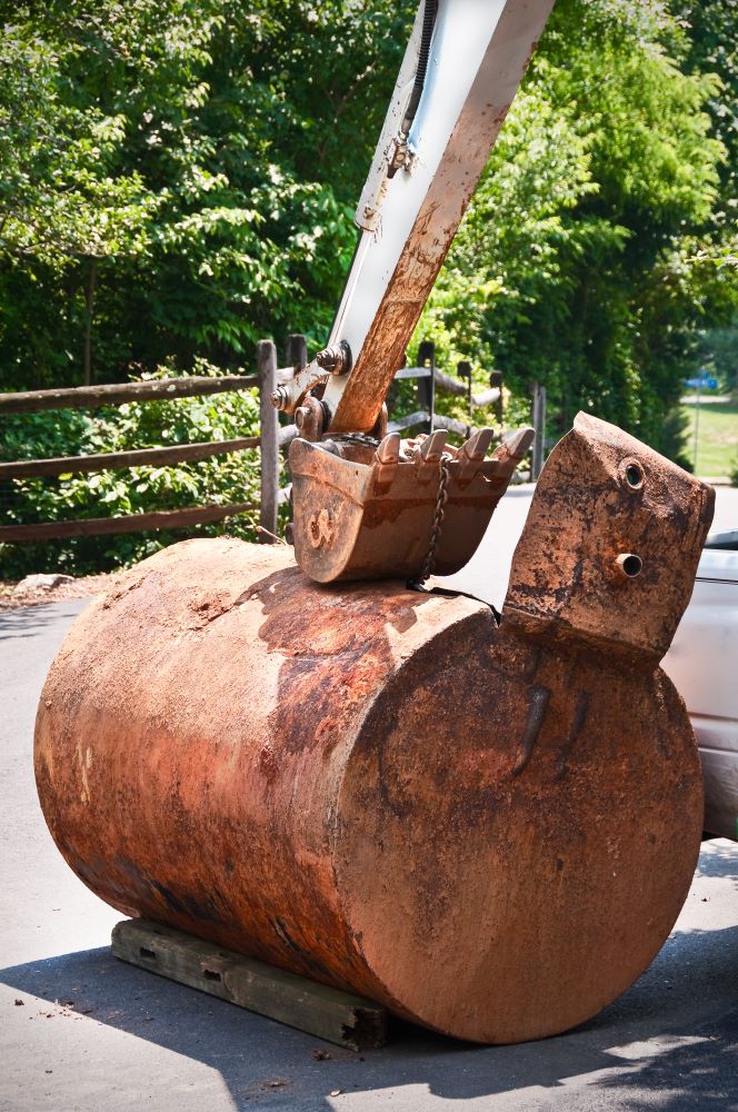 Old, rusted oil tank with construction equipment from being recently dug up.