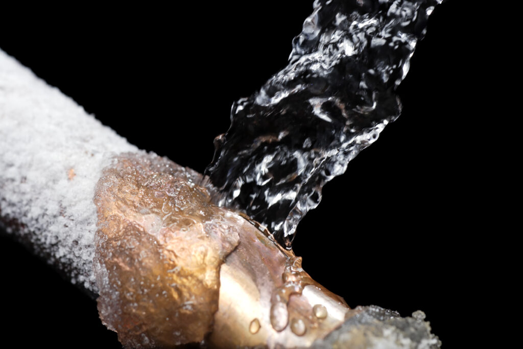 Water pipe frozen as one would see during a cold weather winter home inspection, with water exploding from a break in the pipe.