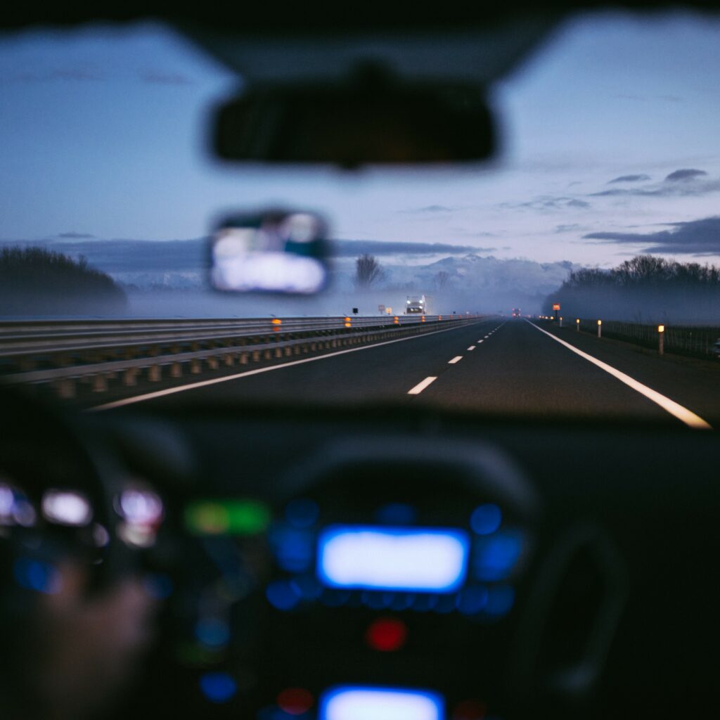 View outside someone's front windshield at dusk on the freeway.