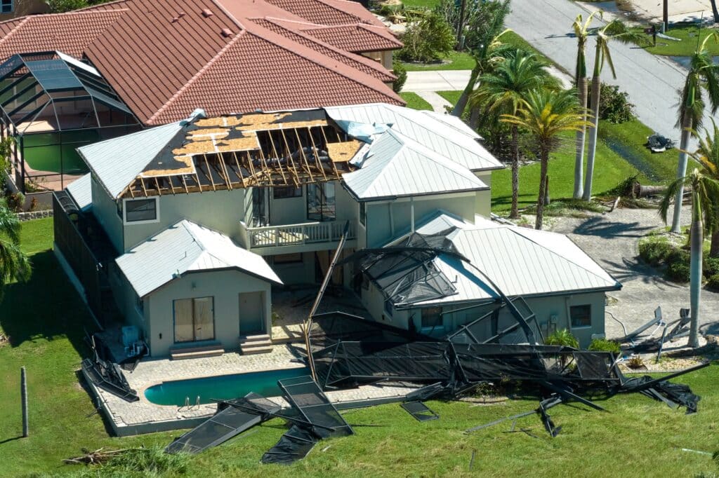 Overhead shot of a multilevel home in Florida with a pool, featuring the roof and shutters blown off as a result of Hurricane Ian. State variations of the fl wind mitigation inspection form are intended to prevent damages like these.