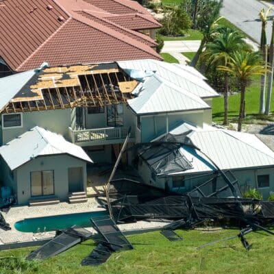 Overhead shot of a multilevel home in Florida with a pool, featuring the roof and shutters blown off as a result of Hurricane Ian. State variations of the fl wind mitigation inspection form are intended to prevent damages like these.