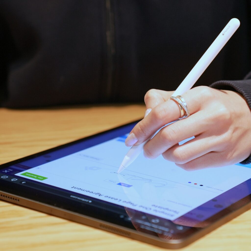 Close-up image of a woman's hand while signing a contract on a tablet.