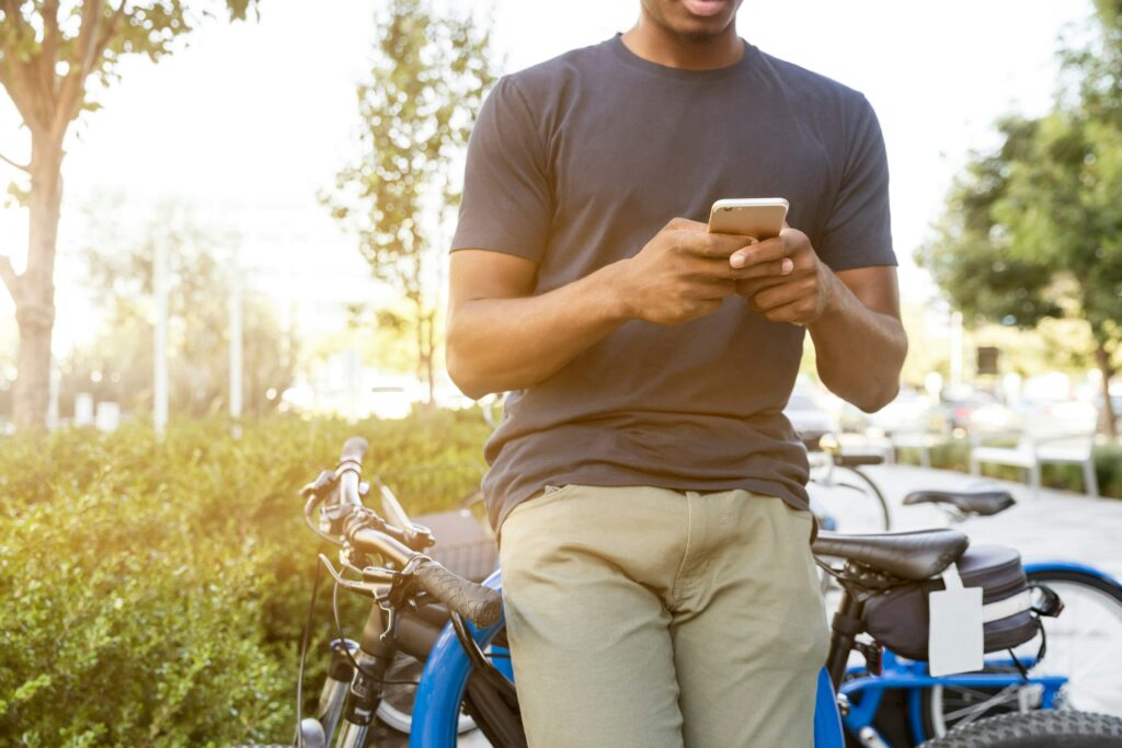 Man sits on a bike while texting on a phone, as if asking about being a home inspector fact witness.