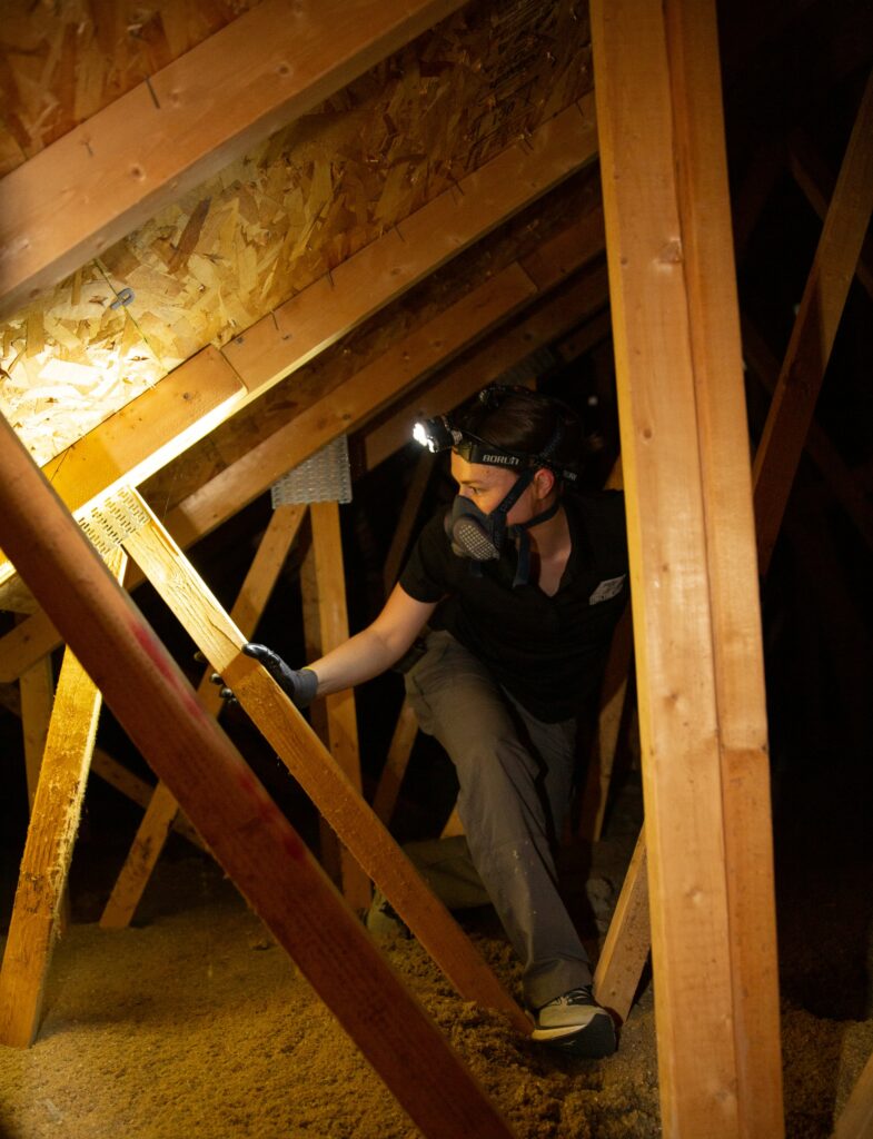 Structure Tech Inspections home inspector wearing a headlamp and walking around an attic.