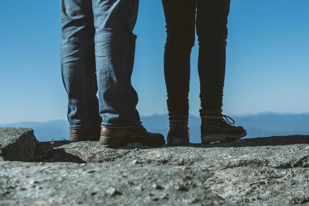 Two sets of legs, man’s and woman’s, each wearing jeans and hiking boots facing away from the camera–as if they’re taking the first steps to start a business.